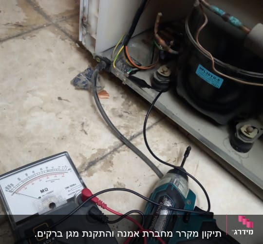 מד מתח ומברגה ליד מדחס מקרר פתוח